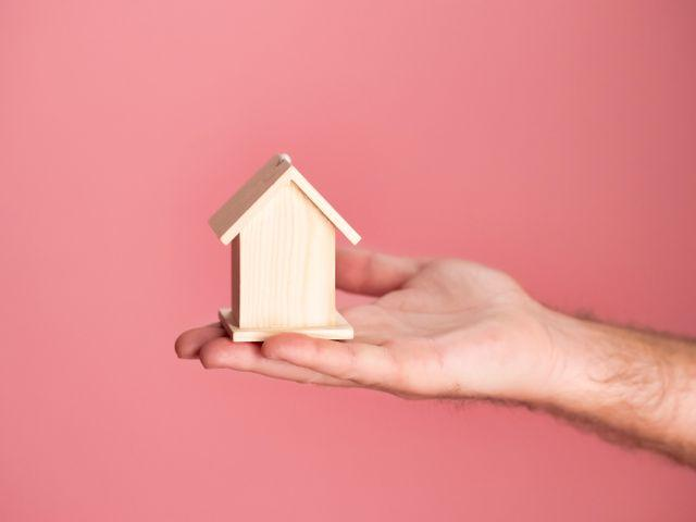 a hand holding a small wooden house model